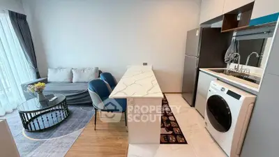 Modern open-layout living room with kitchen, featuring marble island and cozy seating area.