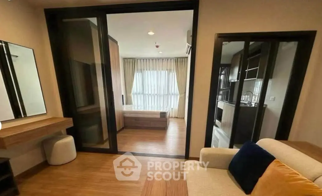 Modern apartment interior with cozy living area and bedroom view, featuring sleek furniture and natural light.