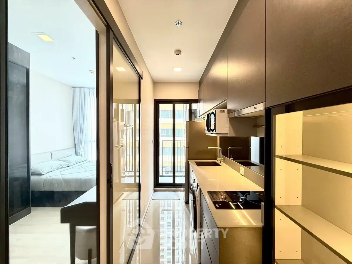 Modern kitchen with sleek appliances and view into a cozy bedroom