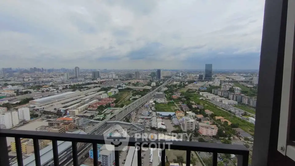 Stunning cityscape view from high-rise balcony overlooking urban skyline and railway tracks.