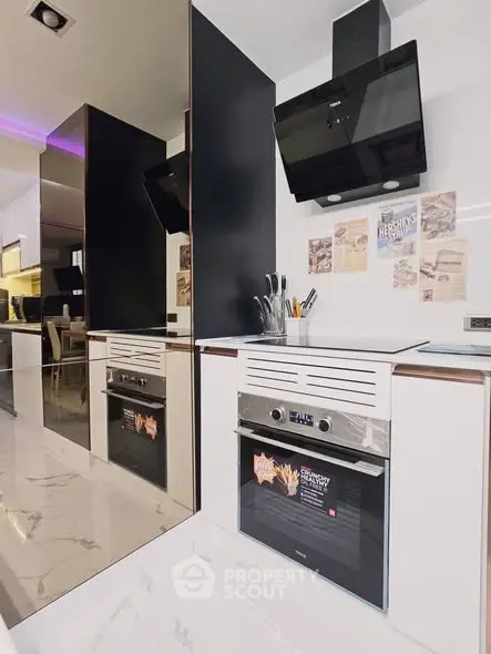 Modern kitchen with sleek appliances and stylish design, featuring a built-in oven and contemporary cabinetry.