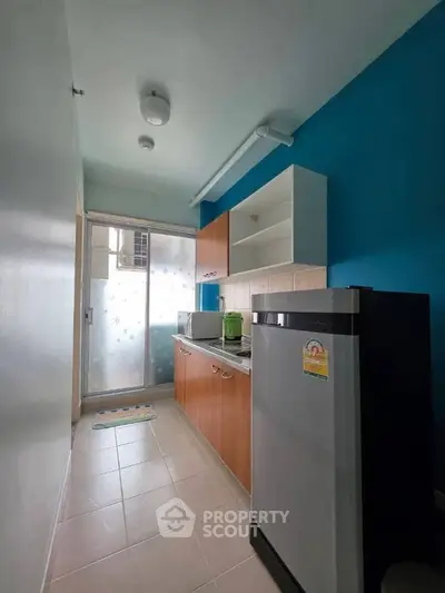 Compact kitchen with modern appliances and vibrant blue accent wall, perfect for efficient cooking.