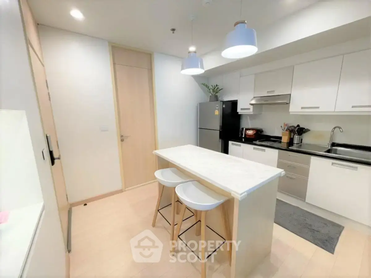 Modern kitchen with island, sleek cabinetry, and pendant lighting in a stylish apartment.