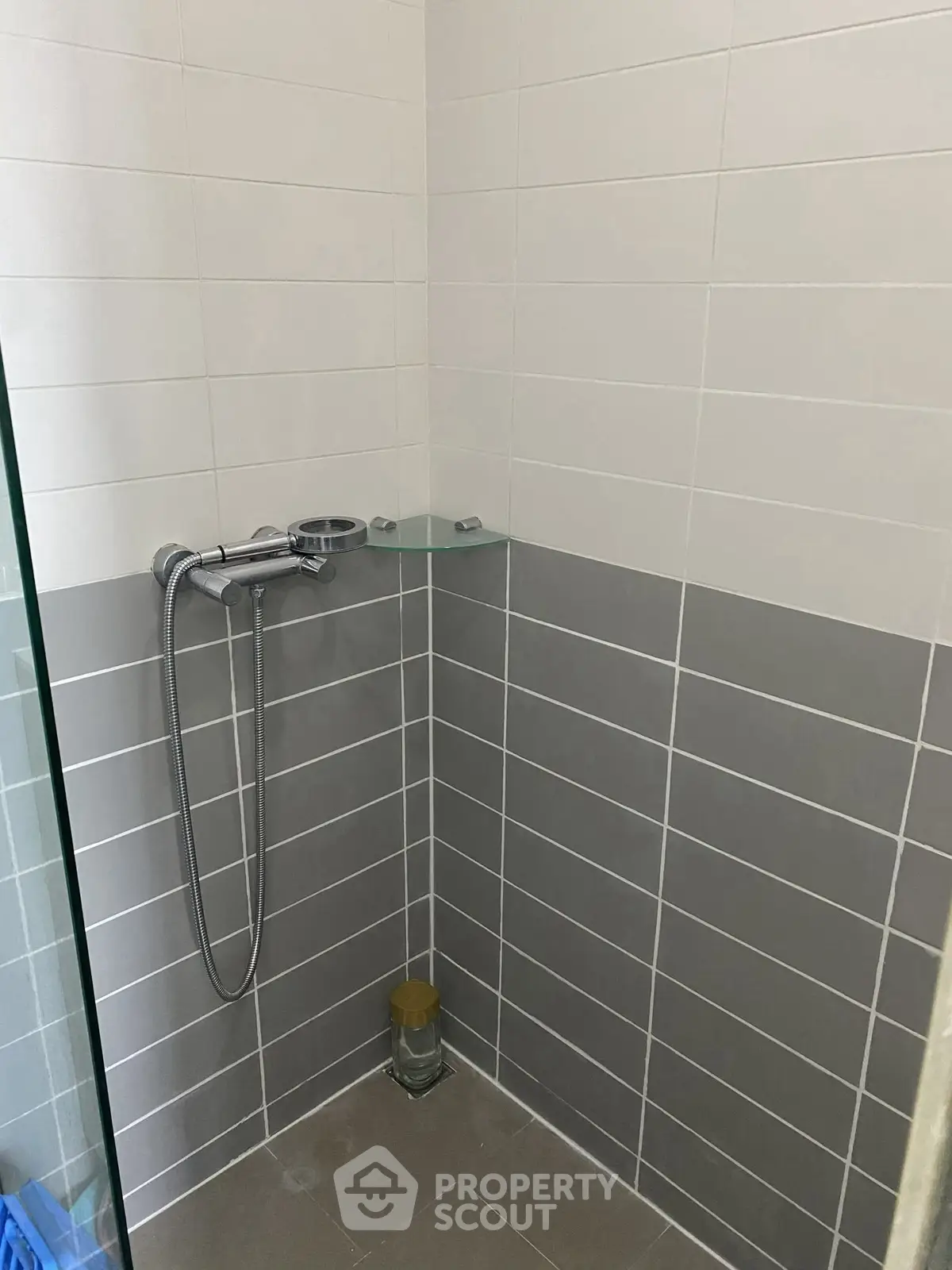 Modern bathroom with sleek gray and white tiles and a glass shower partition.