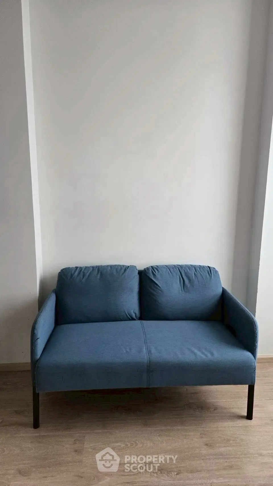 Modern blue sofa in minimalist living room with wooden flooring.