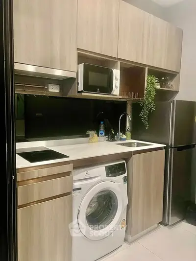 Modern kitchen with sleek cabinets, washing machine, and stainless steel appliances.