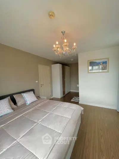 Spacious bedroom with elegant chandelier and cozy decor