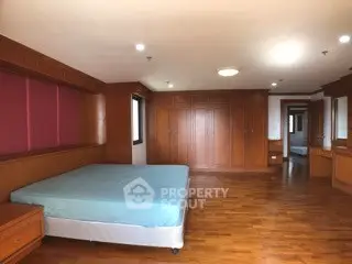 Spacious bedroom with wooden flooring and built-in wardrobes in a luxury apartment.