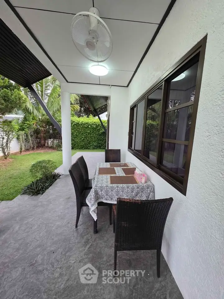 Charming outdoor patio with dining set and garden view, perfect for relaxation and entertaining guests.