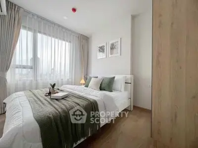 Elegant bedroom with large window, cozy bedding, and stylish decor in modern apartment.