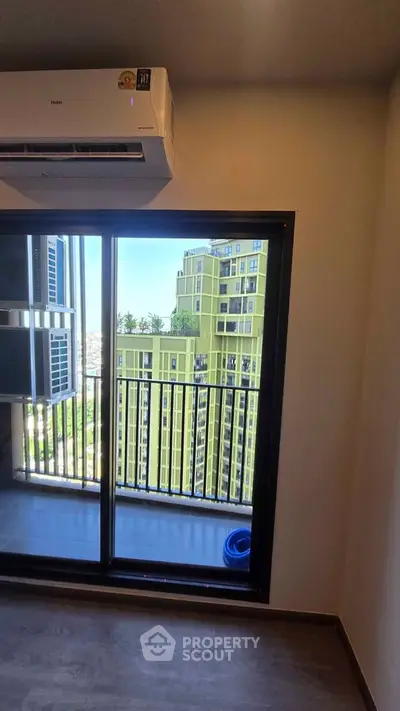 Modern apartment with balcony and city view, featuring sleek air conditioning unit and large sliding glass doors.