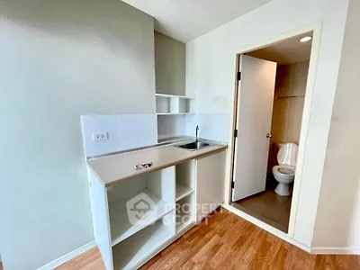 Compact kitchen with open shelving next to a small bathroom in a modern apartment.