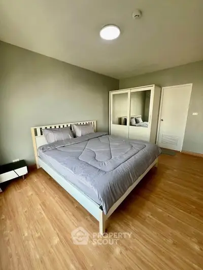 Spacious bedroom with modern decor and wooden flooring, featuring a comfortable bed and mirrored wardrobe.