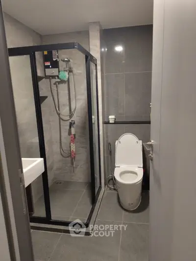 Modern bathroom with glass shower and sleek fixtures in contemporary apartment.
