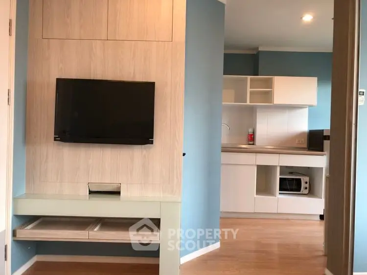 Modern apartment interior with sleek kitchen and mounted TV, showcasing open layout and stylish design.