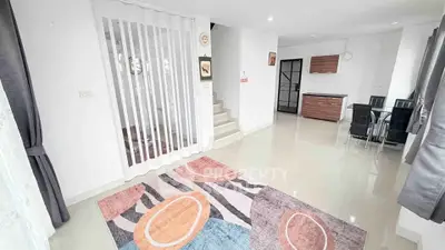 Spacious modern living area with dining set and staircase in bright open layout.