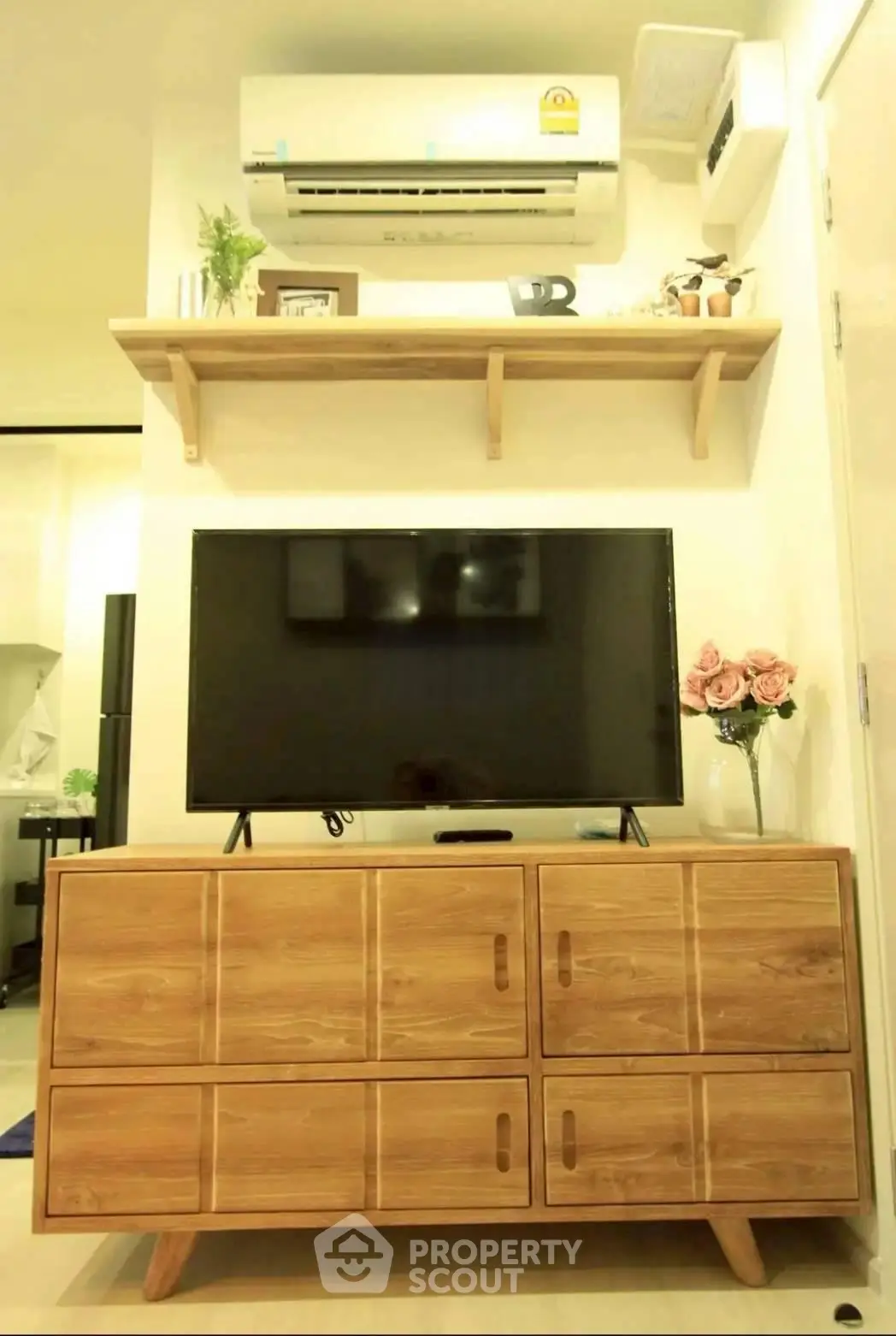 Modern living room with stylish wooden TV stand and wall-mounted air conditioner.