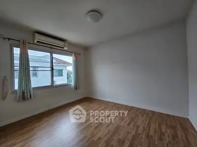 Spacious empty room with wooden flooring and large window, perfect for customization.