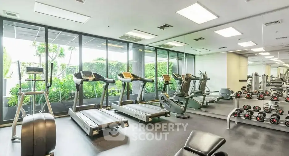 Modern gym with state-of-the-art equipment and lush garden views, perfect for fitness enthusiasts.