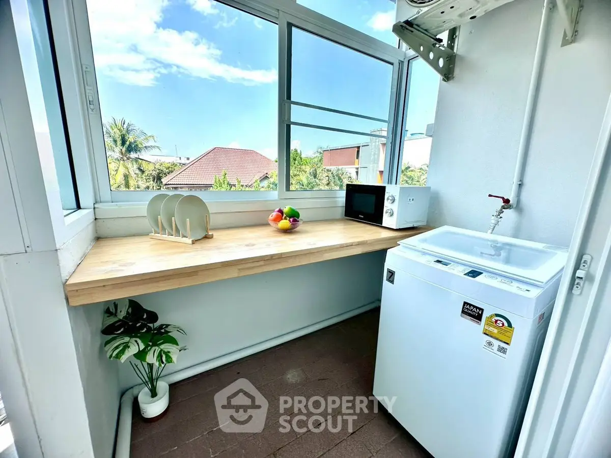 Bright laundry area with washing machine and countertop, featuring large windows and scenic view.