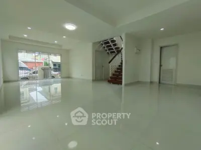 Spacious modern living room with glossy tiled floors and staircase, perfect for family gatherings.