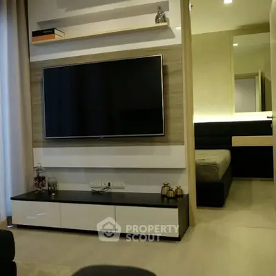 Modern living room with wall-mounted TV and view into cozy bedroom