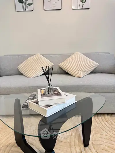 Modern living room with stylish glass coffee table and cozy gray sofa, perfect for relaxation.