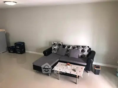Spacious living room with modern gray sectional sofa and sleek tiled flooring.