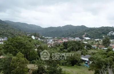 Scenic view of lush green landscape with residential area and mountains in the background.