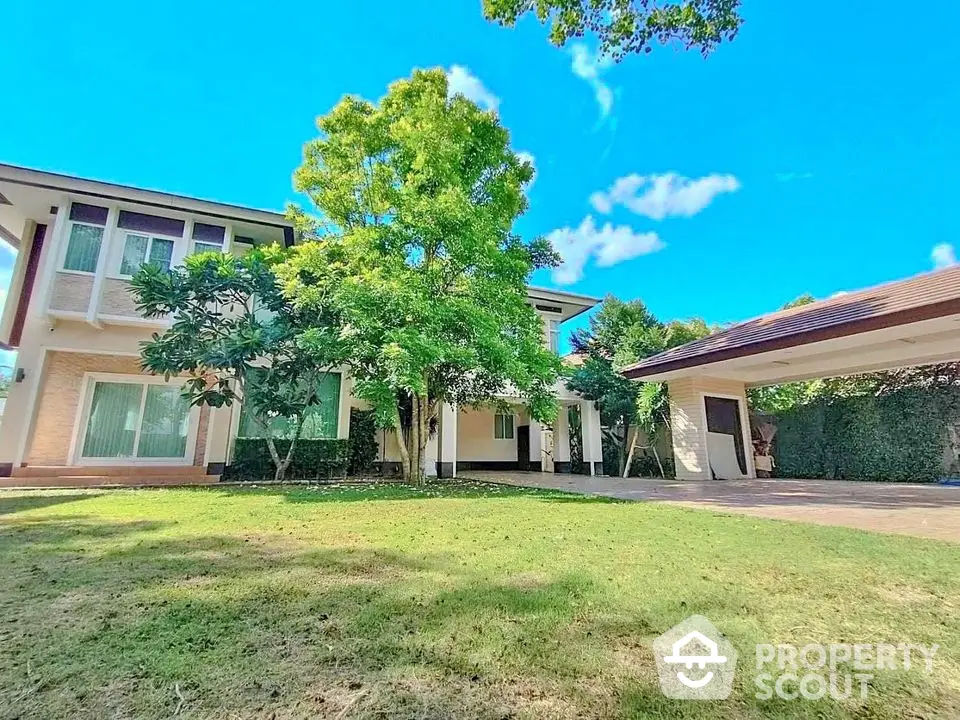 Stunning two-story house with lush garden and spacious driveway under clear blue sky.