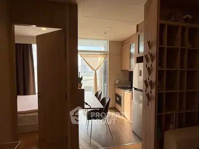Modern apartment interior with open kitchen and dining area, featuring wooden cabinetry and natural light.