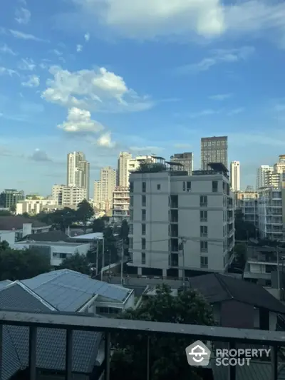 Stunning cityscape view from a high-rise balcony showcasing urban skyline and blue skies.