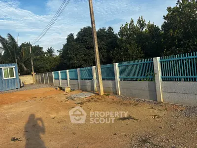Spacious outdoor area with secure fencing and lush greenery, ideal for development opportunities.