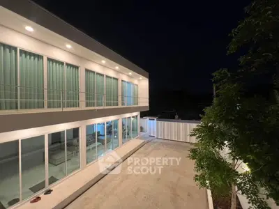 Modern two-story home with large windows and spacious outdoor area at night.