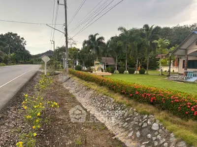 Charming suburban property with lush garden and palm trees along a quiet road.