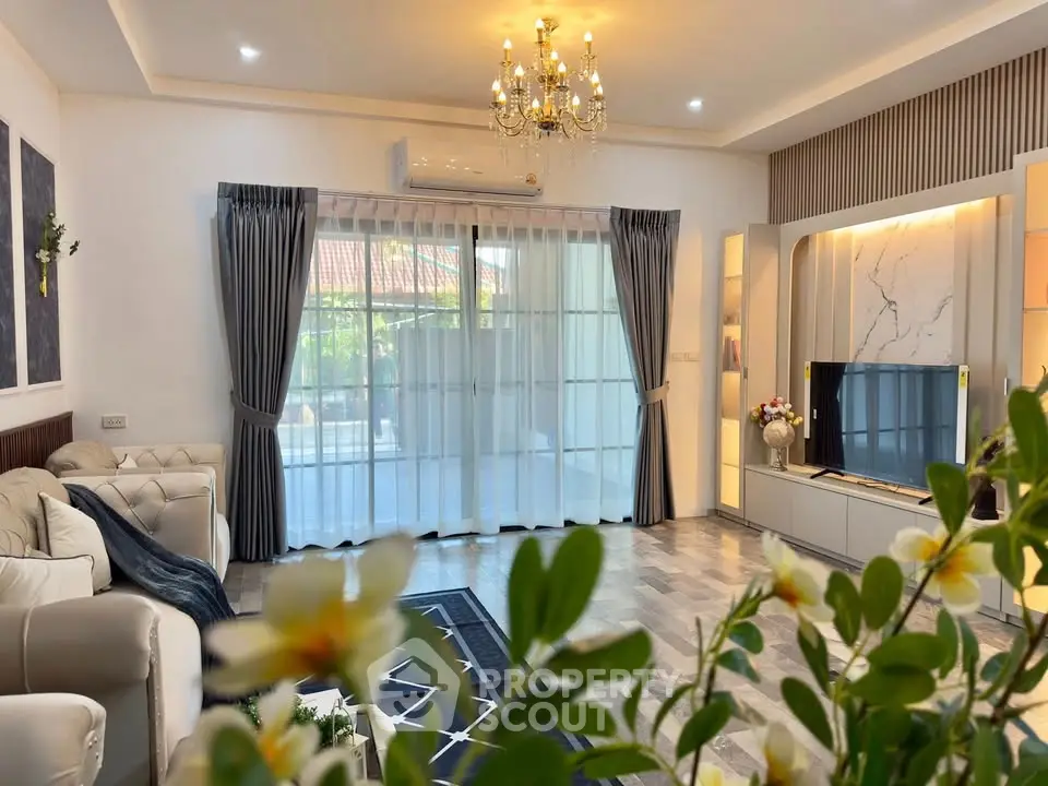 Elegant living room with chandelier, large windows, and modern decor in a spacious home.