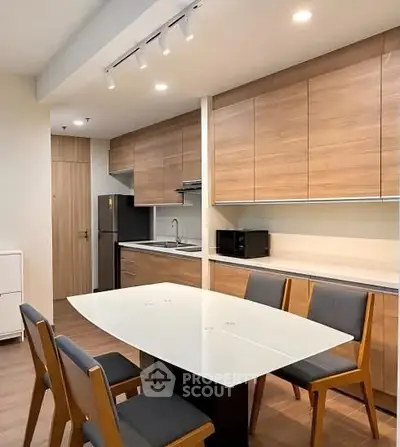 Modern kitchen with sleek wooden cabinets and dining area in contemporary apartment.