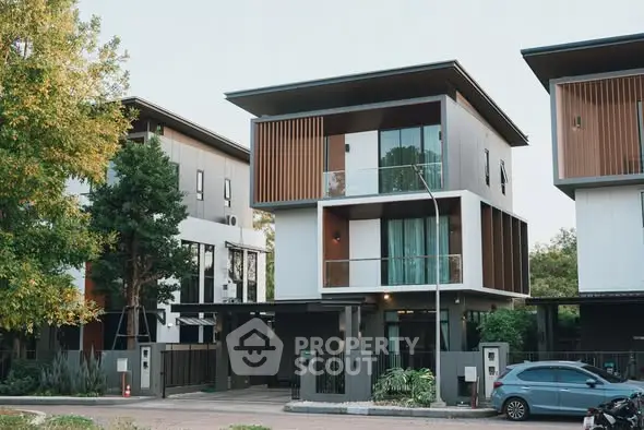 Modern three-story house with sleek design and large windows in a suburban neighborhood.
