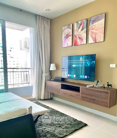 Modern living room with balcony view, stylish decor, and wall-mounted TV in a cozy apartment.