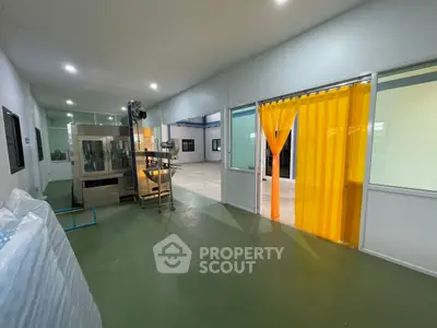Spacious industrial facility with modern equipment and bright yellow partition curtains.