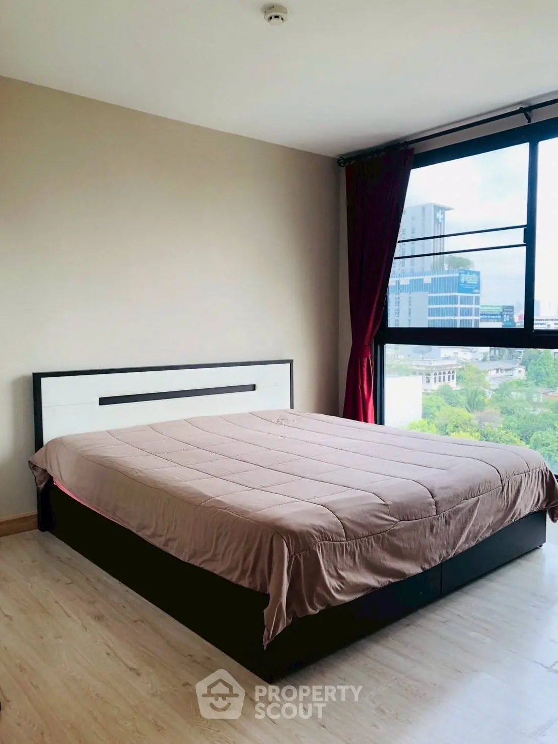 Spacious bedroom with large window offering city views in modern apartment.