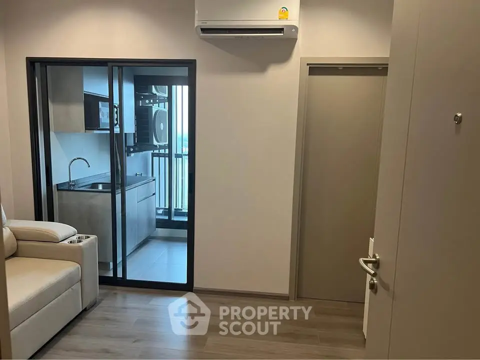 Modern apartment interior with sleek kitchen and balcony view, featuring air conditioning and stylish flooring.
