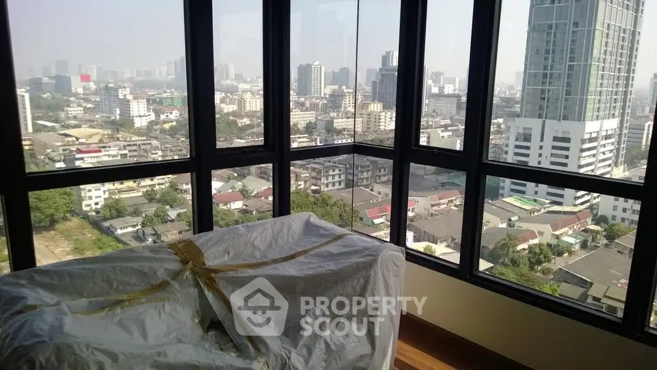 Stunning cityscape view from high-rise apartment with large windows and natural light.