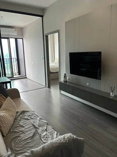 Modern living room with sleek TV setup and view of bedroom and balcony.