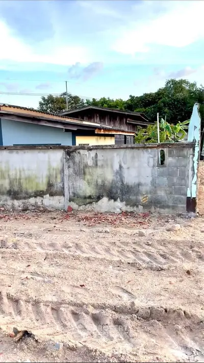 Vacant land with potential for development, featuring a partially constructed wall and adjacent residential buildings.