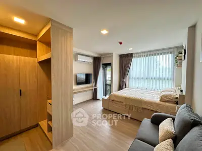Spacious modern studio apartment with cozy living area and large windows for natural light.
