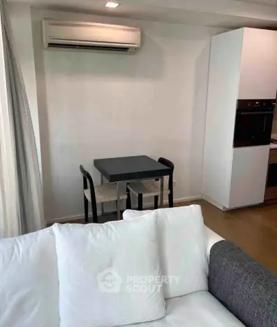 Cozy living room with compact dining area and modern kitchen appliances.