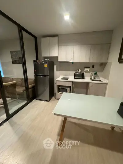 Modern compact kitchen with sleek appliances and open layout, adjacent to cozy living area.