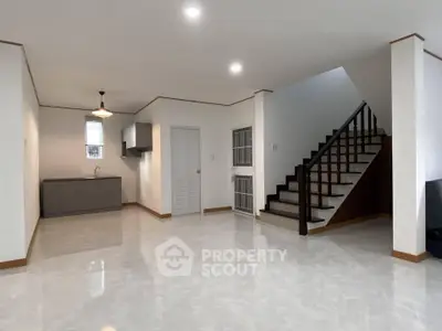 Spacious open-plan living area with modern staircase and sleek kitchen corner.