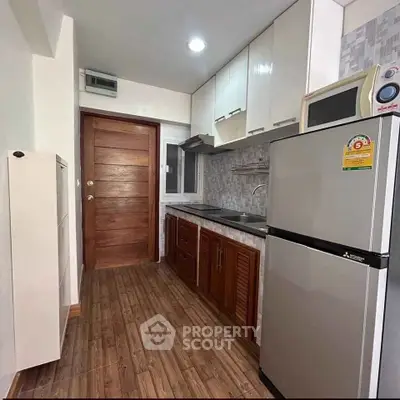 Modern kitchen with wooden cabinets and stainless steel appliances in a cozy apartment.